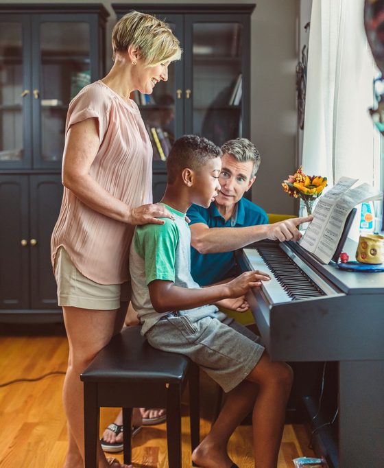 A family gathered around the piano during a music lesson